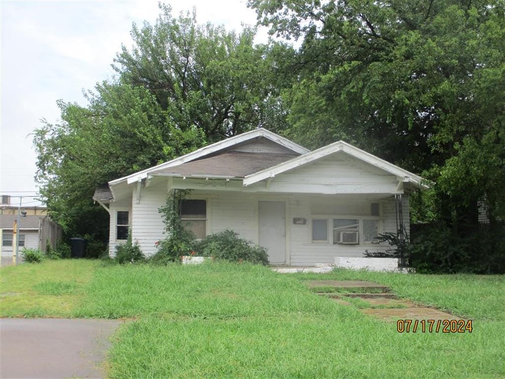 view of front of home with cooling unit and a front yard