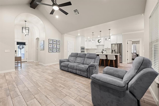 living room featuring arched walkways, high vaulted ceiling, ceiling fan with notable chandelier, visible vents, and beam ceiling