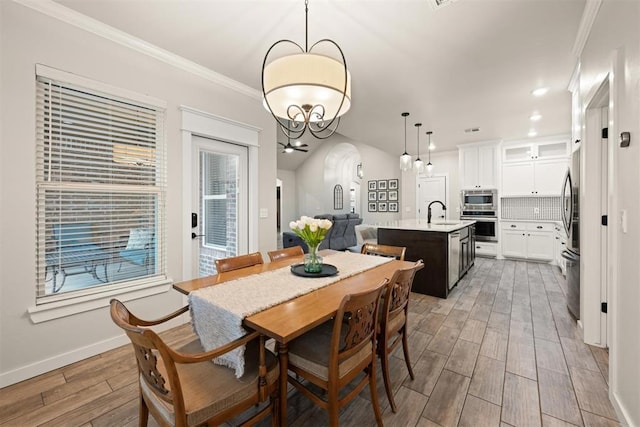 dining area with arched walkways, baseboards, ornamental molding, wood tiled floor, and recessed lighting