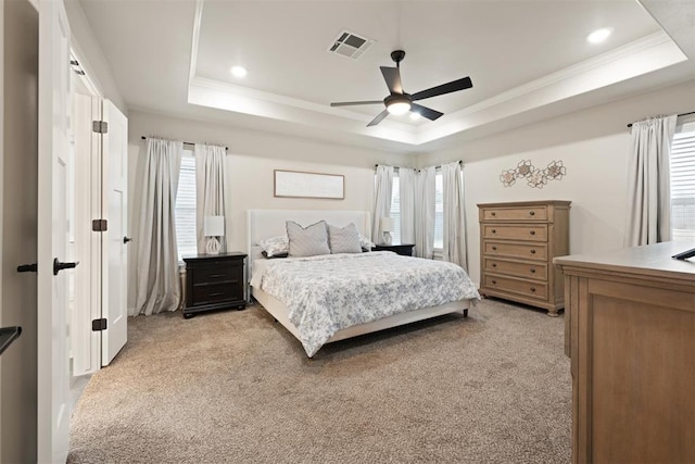 bedroom with visible vents, a raised ceiling, and light colored carpet