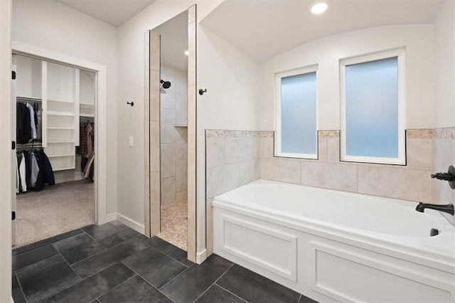 bathroom with a stall shower, a spacious closet, and a bath