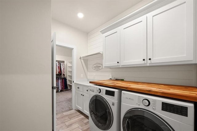 laundry area featuring light wood-style flooring, washing machine and clothes dryer, and cabinet space