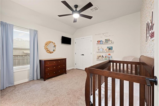 bedroom with lofted ceiling, a closet, light colored carpet, visible vents, and baseboards