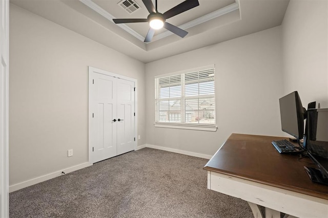 carpeted office space with baseboards, visible vents, a raised ceiling, a ceiling fan, and crown molding