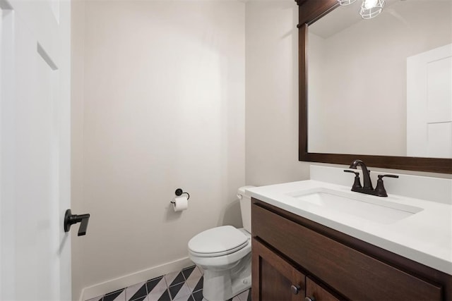 bathroom featuring baseboards, vanity, and toilet