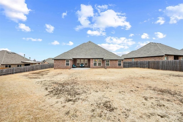 rear view of house with a patio area, a fenced backyard, and brick siding