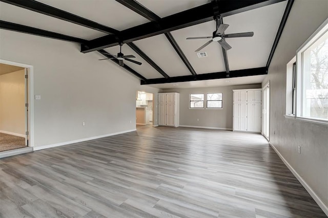 unfurnished living room with vaulted ceiling with beams, ceiling fan, and light wood-type flooring