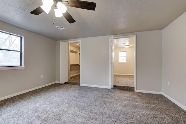 unfurnished bedroom with ceiling fan, carpet, and a textured ceiling