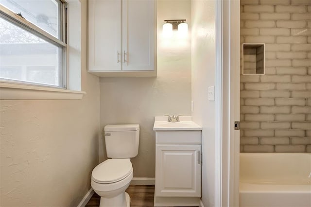 bathroom featuring vanity, hardwood / wood-style floors, a tub, and toilet