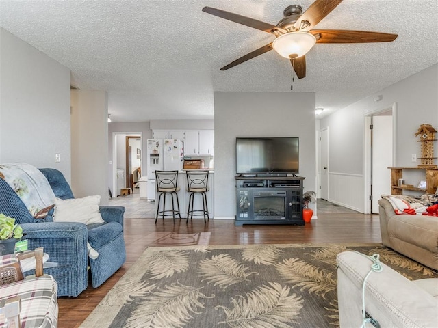 living room with ceiling fan, dark hardwood / wood-style flooring, and a textured ceiling