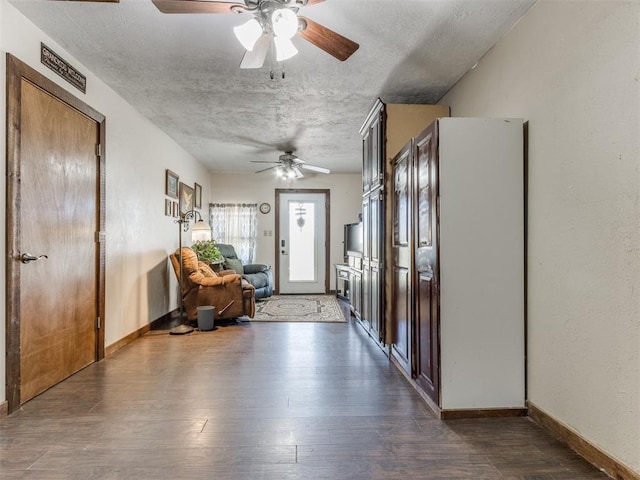 entrance foyer with ceiling fan, dark wood-type flooring, and a textured ceiling