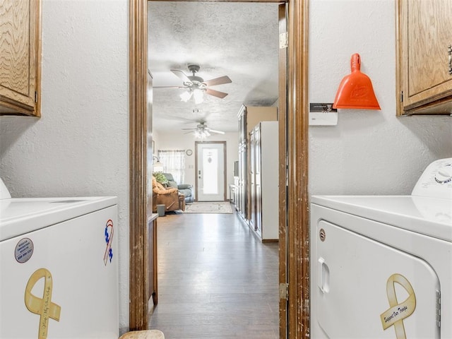 clothes washing area featuring cabinets, light hardwood / wood-style flooring, a textured ceiling, and washing machine and clothes dryer