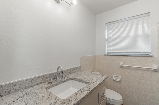 bathroom with vanity, toilet, and tile walls