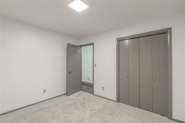 unfurnished bedroom with light colored carpet and a closet