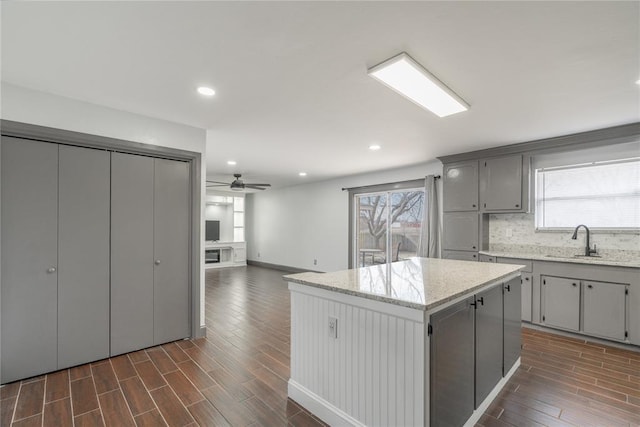 kitchen with gray cabinets, sink, decorative backsplash, a center island, and a healthy amount of sunlight