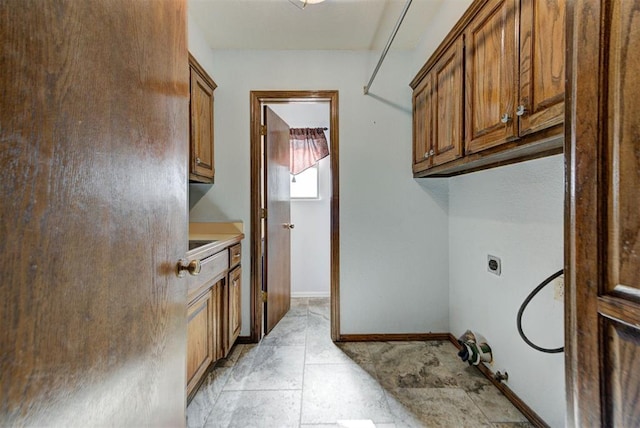 clothes washing area featuring hookup for an electric dryer, baseboards, and cabinet space