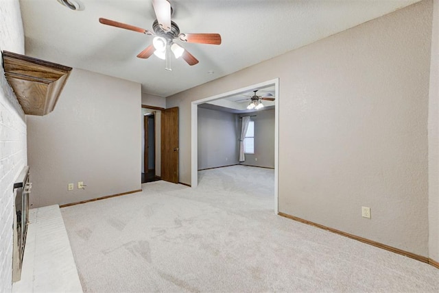 unfurnished room featuring a fireplace, ceiling fan, light carpet, and baseboards