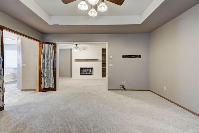 unfurnished room featuring ceiling fan, carpet flooring, baseboards, and a fireplace