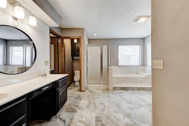 bathroom featuring a sink, toilet, a textured ceiling, double vanity, and a stall shower