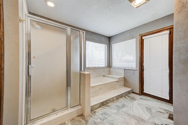 bathroom with a shower stall, a bath, and a textured ceiling
