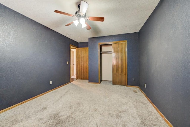 unfurnished bedroom with a closet, a textured wall, baseboards, and carpet floors