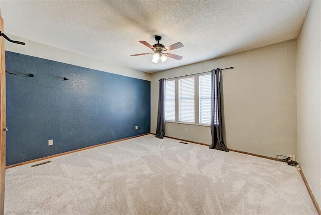 empty room featuring visible vents, baseboards, a ceiling fan, and carpet