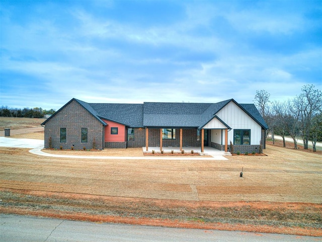 modern farmhouse featuring covered porch and a front yard