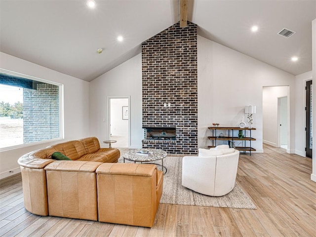 living room with beamed ceiling, high vaulted ceiling, a fireplace, and light hardwood / wood-style floors