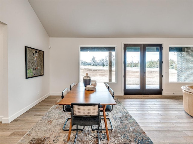 dining room with vaulted ceiling, light hardwood / wood-style floors, and french doors