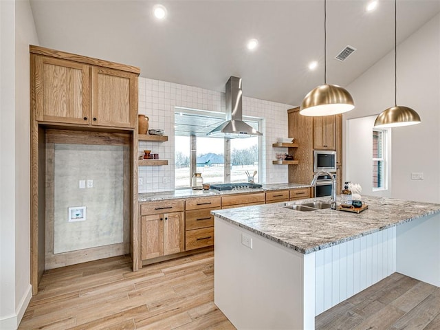 kitchen with sink, light stone counters, hanging light fixtures, appliances with stainless steel finishes, and range hood