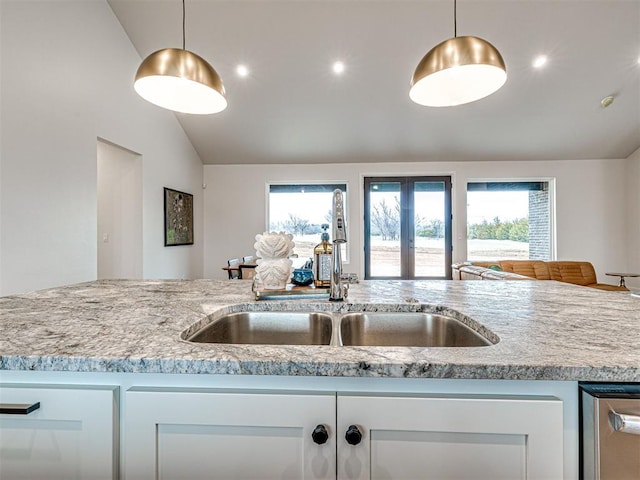 kitchen with vaulted ceiling, sink, white cabinets, and decorative light fixtures