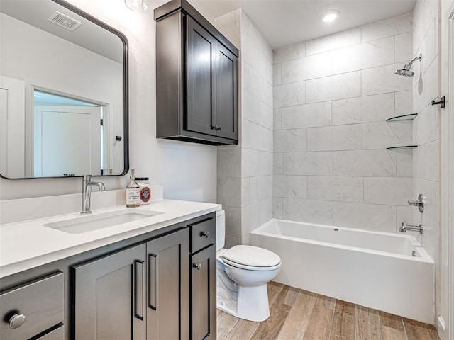 full bathroom featuring vanity, wood-type flooring, toilet, and tiled shower / bath