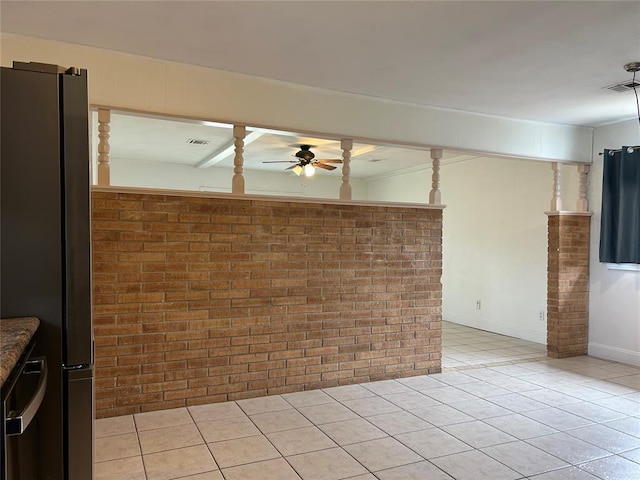 empty room featuring ceiling fan, brick wall, and light tile patterned floors