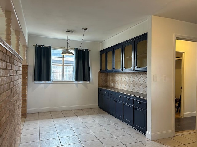 kitchen featuring light tile patterned flooring, blue cabinets, decorative light fixtures, brick wall, and backsplash