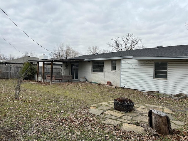 back of property with an outdoor fire pit, a patio area, and a lawn