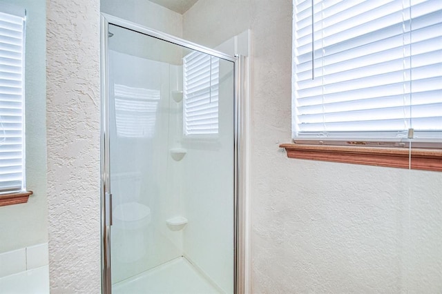 10700 NW 36th Pl, Yukon, OK 73099 - full bathroom featuring a textured wall, a shower stall, and healthy amount of natural light