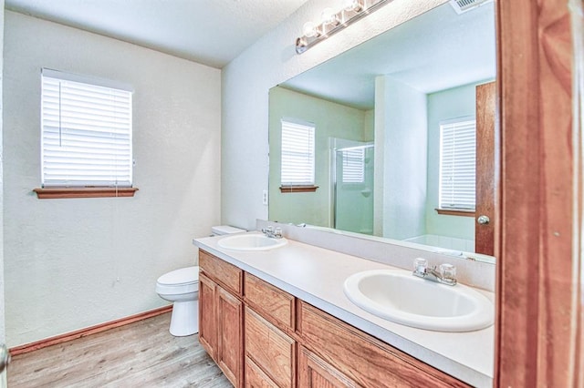 10700 NW 36th Pl, Yukon, OK 73099 - bathroom featuring wood finished floors, a shower stall, baseboards, toilet, and double vanity