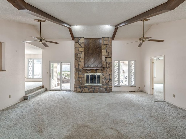 unfurnished living room featuring a stone fireplace, beamed ceiling, light colored carpet, and a textured ceiling