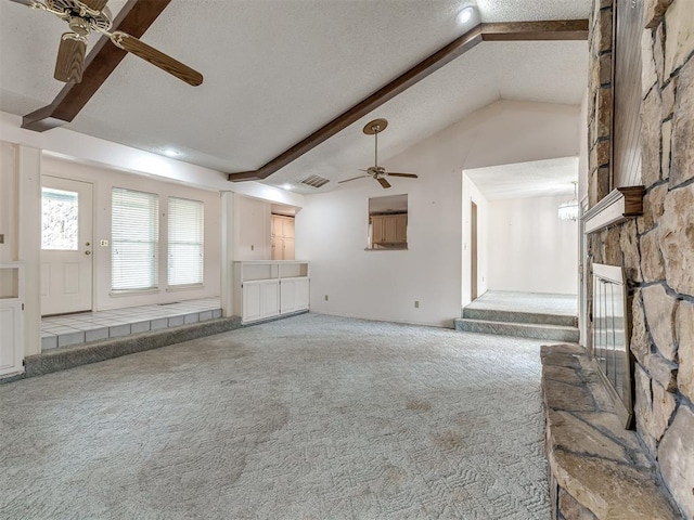 unfurnished living room featuring ceiling fan, vaulted ceiling with beams, carpet, a fireplace, and a textured ceiling