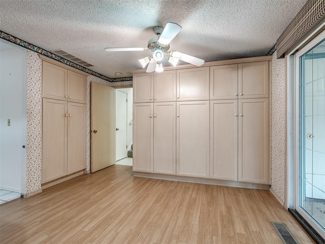 unfurnished bedroom with ceiling fan, a textured ceiling, and light wood-type flooring