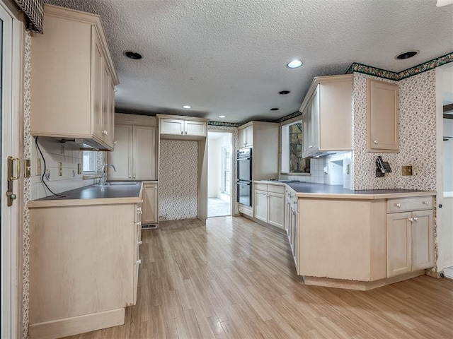 kitchen featuring decorative backsplash, black double oven, a textured ceiling, and light wood-type flooring