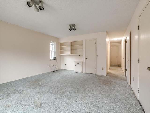 unfurnished living room featuring light colored carpet and a textured ceiling