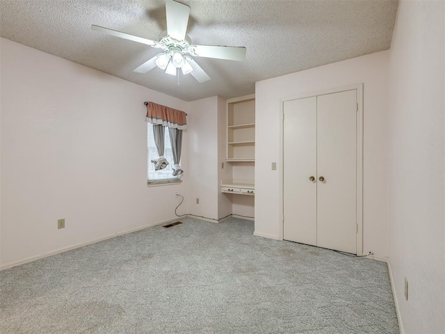 unfurnished bedroom featuring ceiling fan, a closet, light carpet, and a textured ceiling