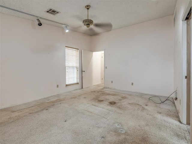 unfurnished room featuring ceiling fan, light colored carpet, track lighting, and a textured ceiling