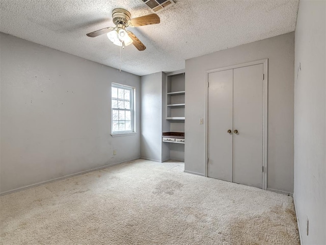 unfurnished bedroom featuring ceiling fan, light carpet, and a textured ceiling