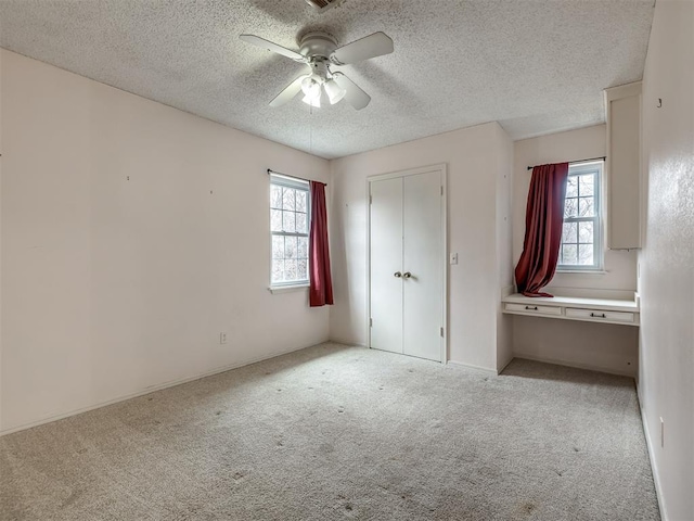 unfurnished bedroom with ceiling fan, light colored carpet, a closet, and a textured ceiling