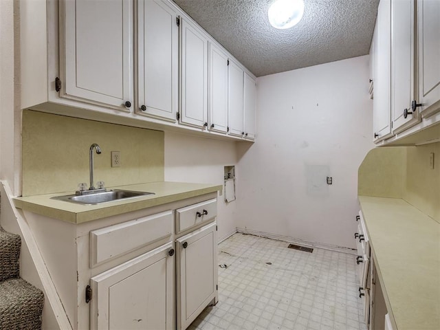 laundry room with cabinets, sink, washer hookup, and a textured ceiling