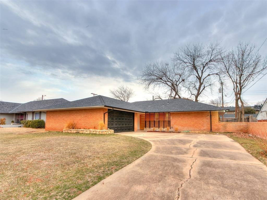 single story home featuring a garage and a front lawn