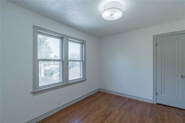 unfurnished room with dark hardwood / wood-style flooring and a textured ceiling