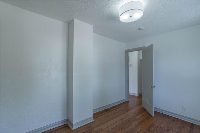 empty room with dark hardwood / wood-style floors and a textured ceiling